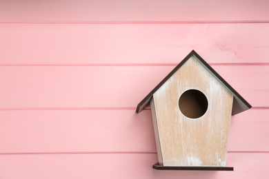 Photo of Beautiful bird house on pink wooden background, space for text