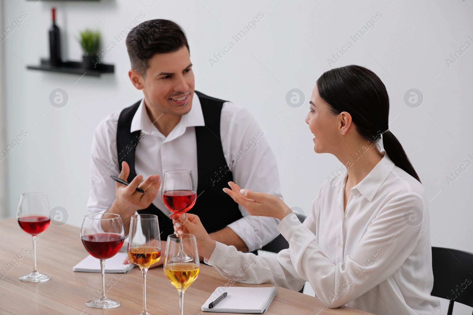 Photo of Sommeliers tasting different sorts of wine at table indoors