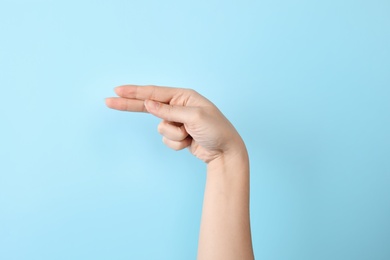 Woman showing H letter on color background, closeup. Sign language