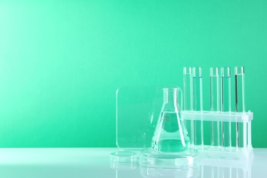 Laboratory analysis. Different glassware on table against green background, space for text