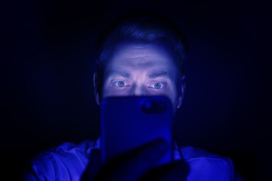 Internet addiction. Man using smartphone at night. Toned in blue