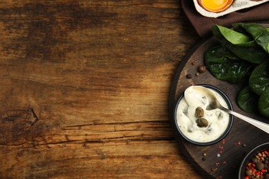 Photo of Caper sauce in bowl on wooden table, flat lay. Space for text