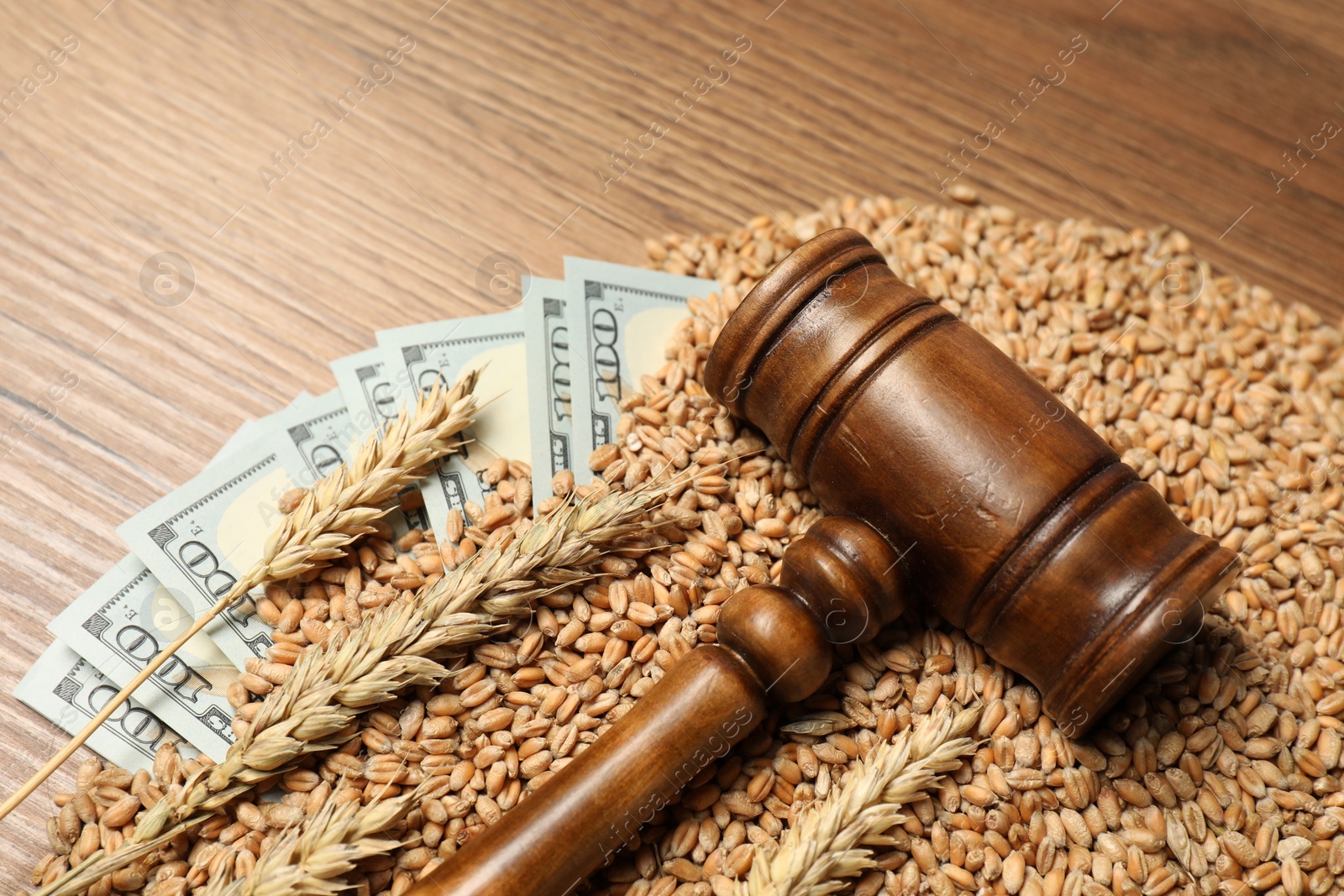 Photo of Agricultural business. Dollar banknotes, judge's gavel, wheat ears and grains on wooden table, closeup. Space for text