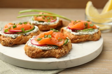 Photo of Tasty canapes with salmon, cucumber, radish and cream cheese on wooden table, closeup
