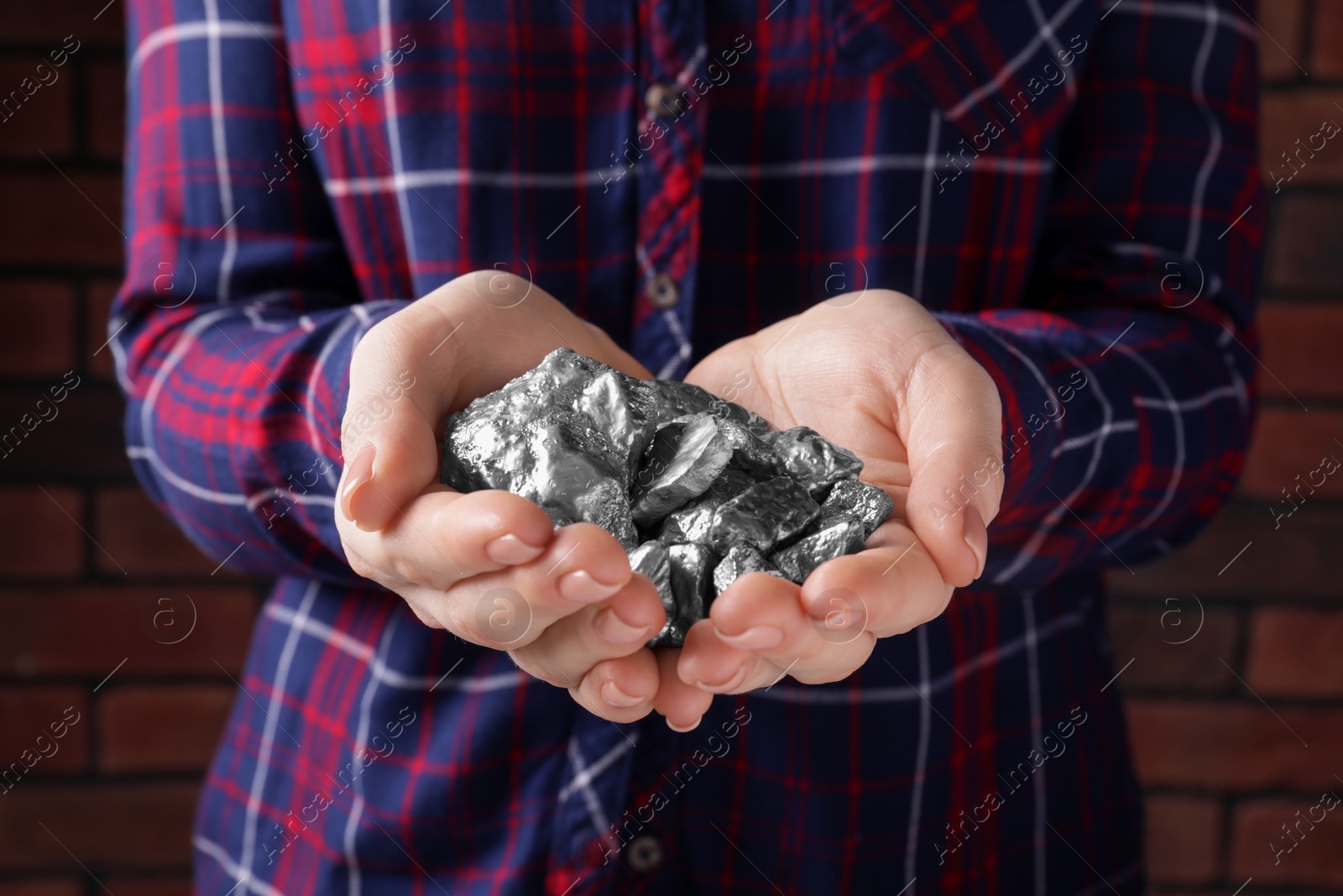 Photo of Woman with silver nuggets against brick background, closeup