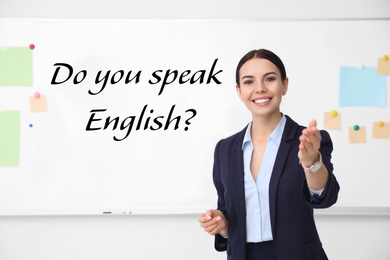 Young English teacher near whiteboard in classroom