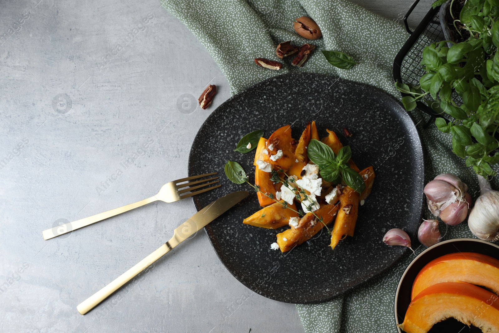 Photo of Baked pumpkin slices served with cheese, thyme, basil and pecans on light table, flat lay. Space for text