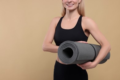 Photo of Athletic woman with fitness mat on beige background, closeup. Space for text