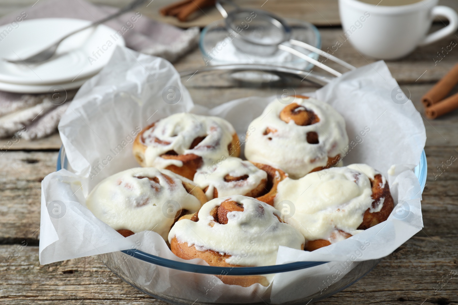 Photo of Tasty cinnamon rolls with cream on wooden table, closeup