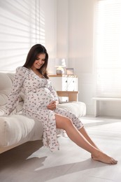 Young pregnant woman sitting on sofa at home