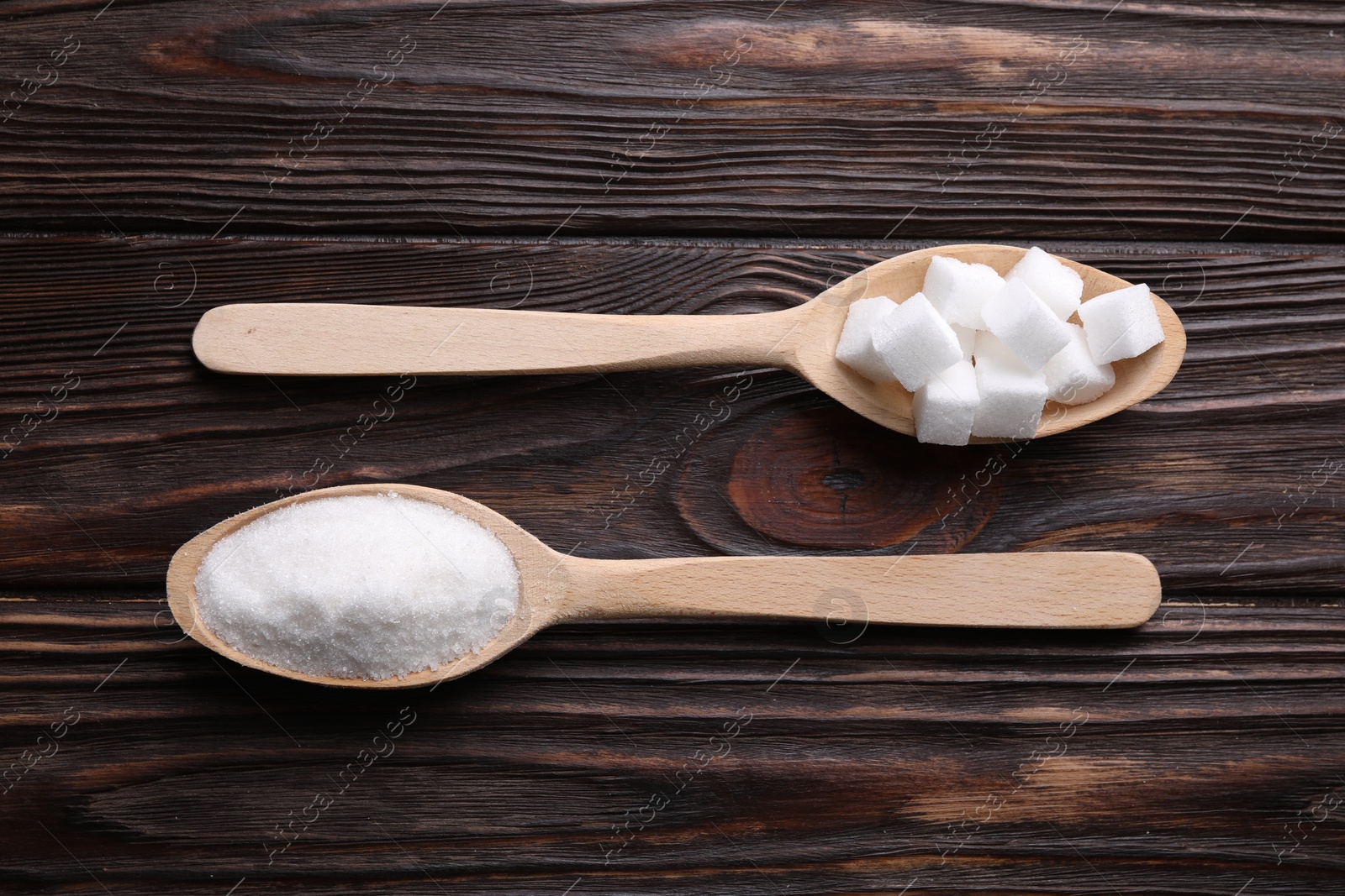 Photo of Spoons with different types of white sugar on wooden table, flat lay