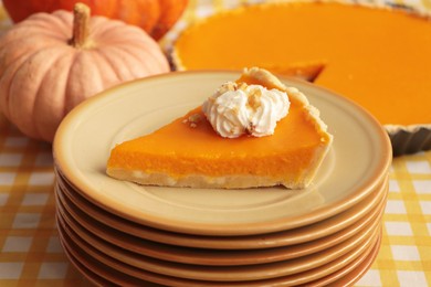 Photo of Stacked plates with piece of fresh homemade pumpkin pie with whipped cream on table