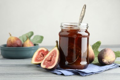 Photo of Jar of tasty sweet jam and fresh figs on grey table, space for text