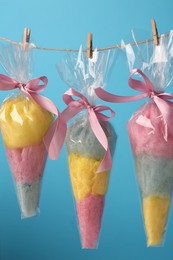 Packaged sweet cotton candies hanging on clothesline against light blue background
