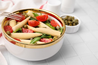 Photo of Tasty baby corn with tomatoes, arugula and capers on white tiled table, closeup