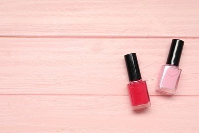 Photo of Nail polishes on pink wooden table, flat lay. Space for text
