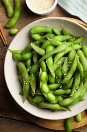 Photo of Green edamame beans in pods served with sesame seeds on wooden table, flat lay