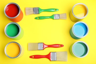 Photo of Flat lay composition with paint cans and brushes on yellow background. Space for text