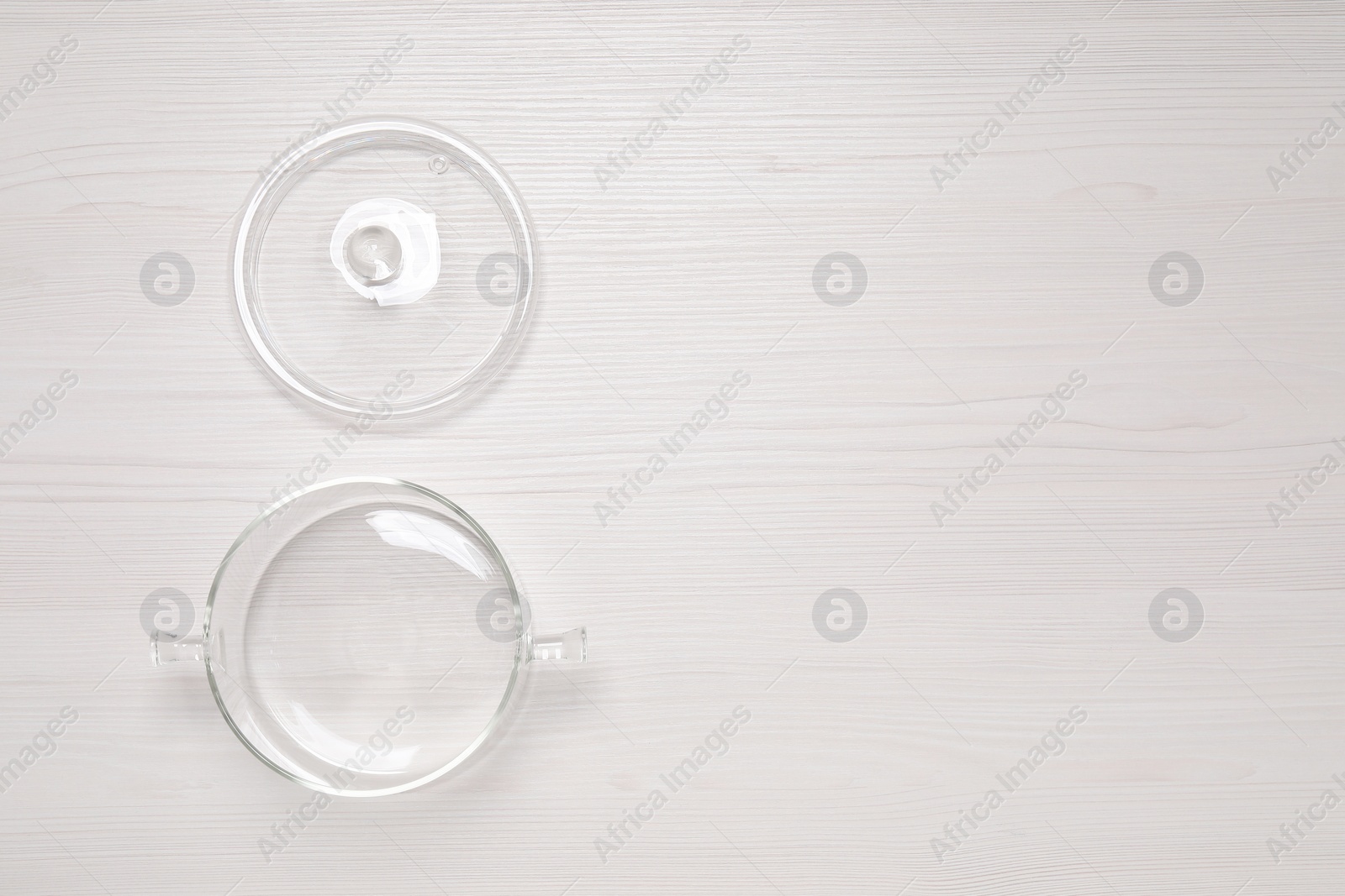 Photo of Empty glass pot and lid on white wooden table, flat lay. Space for text