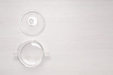 Photo of Empty glass pot and lid on white wooden table, flat lay. Space for text