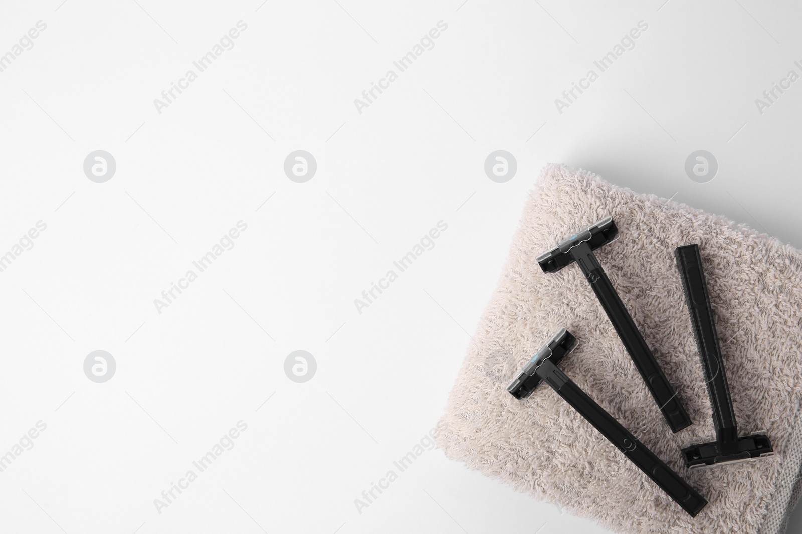 Photo of Razors and towel on white background, top view. Space for text