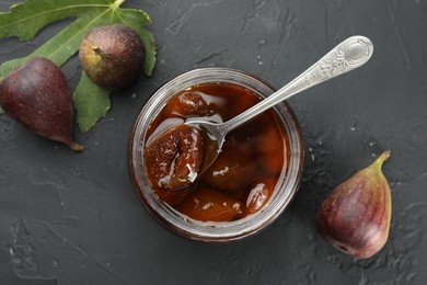Photo of Jar of tasty sweet jam and fresh figs on black table, flat lay