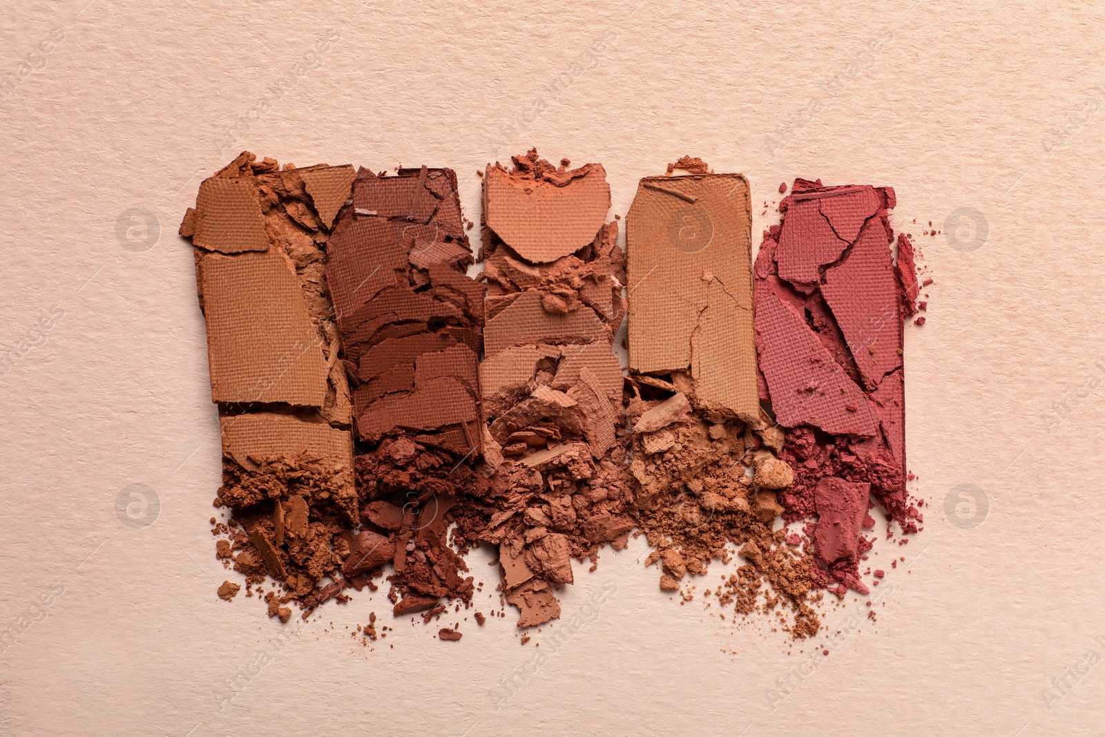 Photo of Different crushed eye shadows on beige background, flat lay