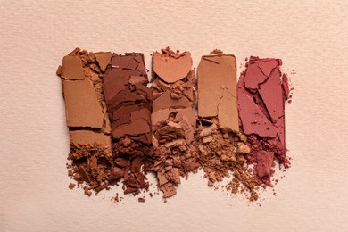 Different crushed eye shadows on beige background, flat lay