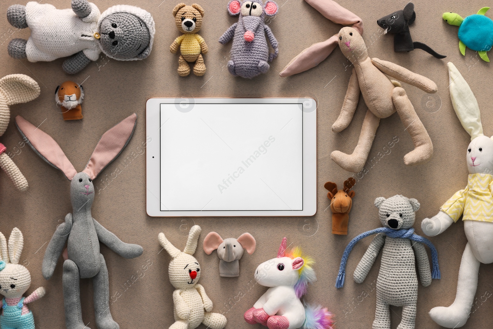 Photo of Modern tablet and kid's toys on light brown background, flat lay. Space for text