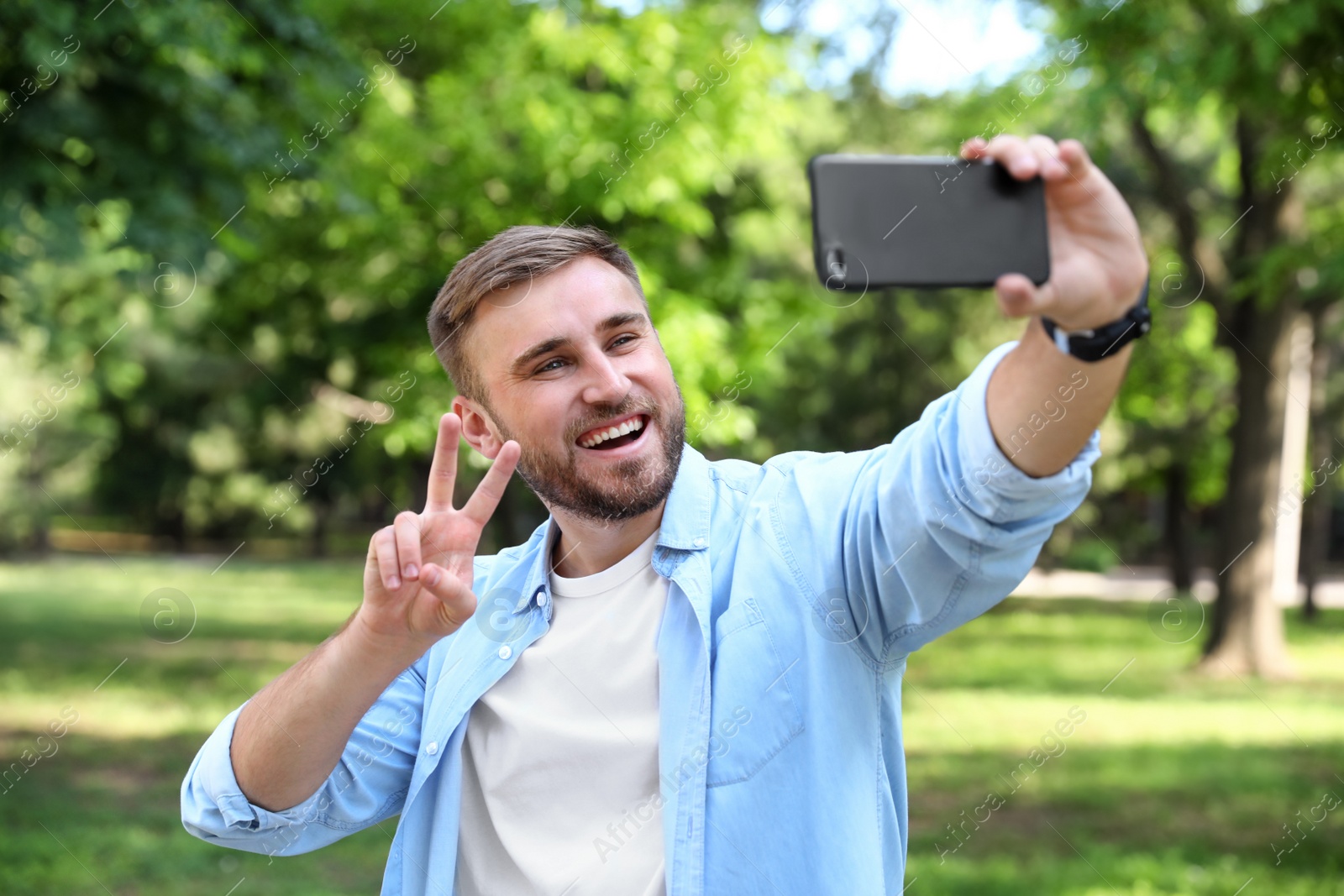 Photo of Happy young man taking selfie in park