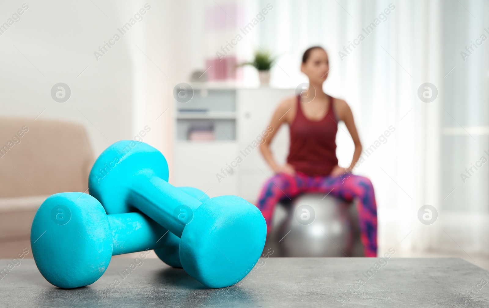 Photo of Woman doing fitness exercise at home, focus on dumbbells. Space for text