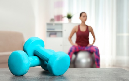 Woman doing fitness exercise at home, focus on dumbbells. Space for text