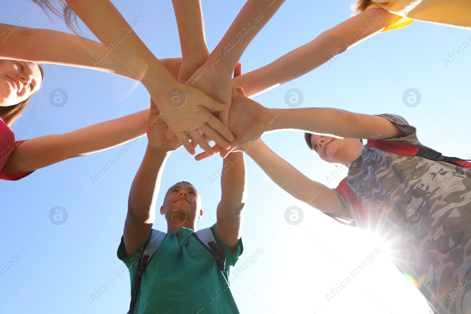 Photo of Group of children putting hands together outdoors. Summer camp