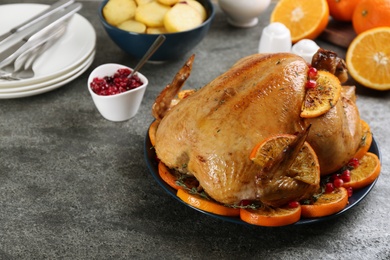 Delicious chicken with oranges and pomegranate on grey table