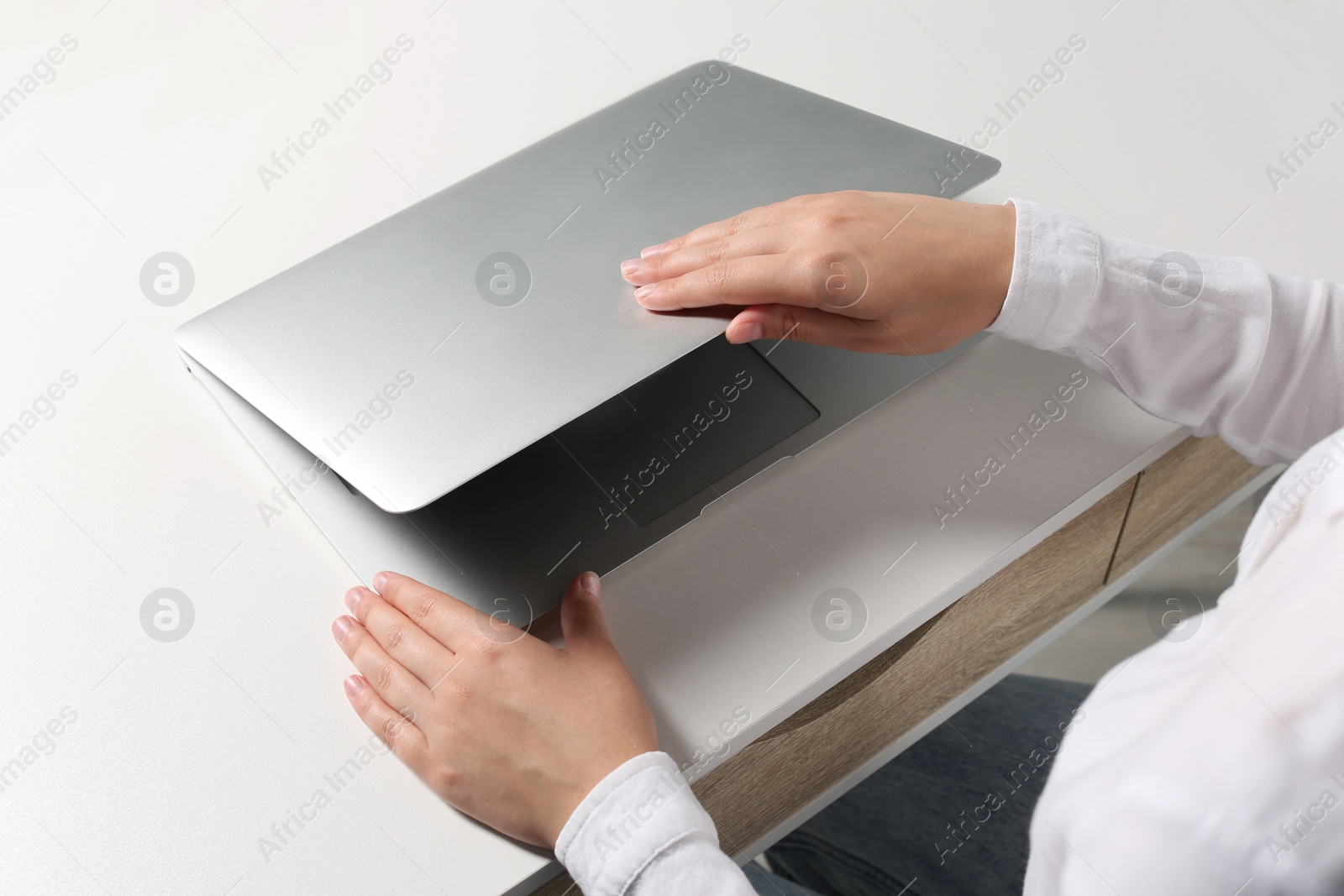 Photo of Woman opening laptop at white table in office, closeup