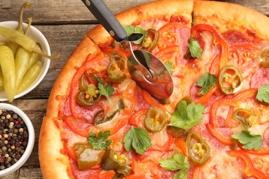 Photo of Cutting delicious pizza Diablo at wooden table, flat lay