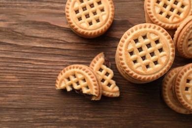 Photo of Tasty sandwich cookies with cream on wooden table, flat lay. Space for text