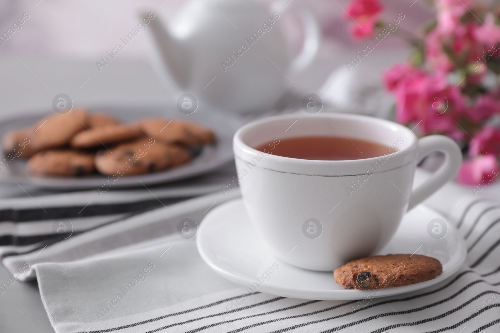 Photo of Cup of aromatic tea and tasty cookies on grey table