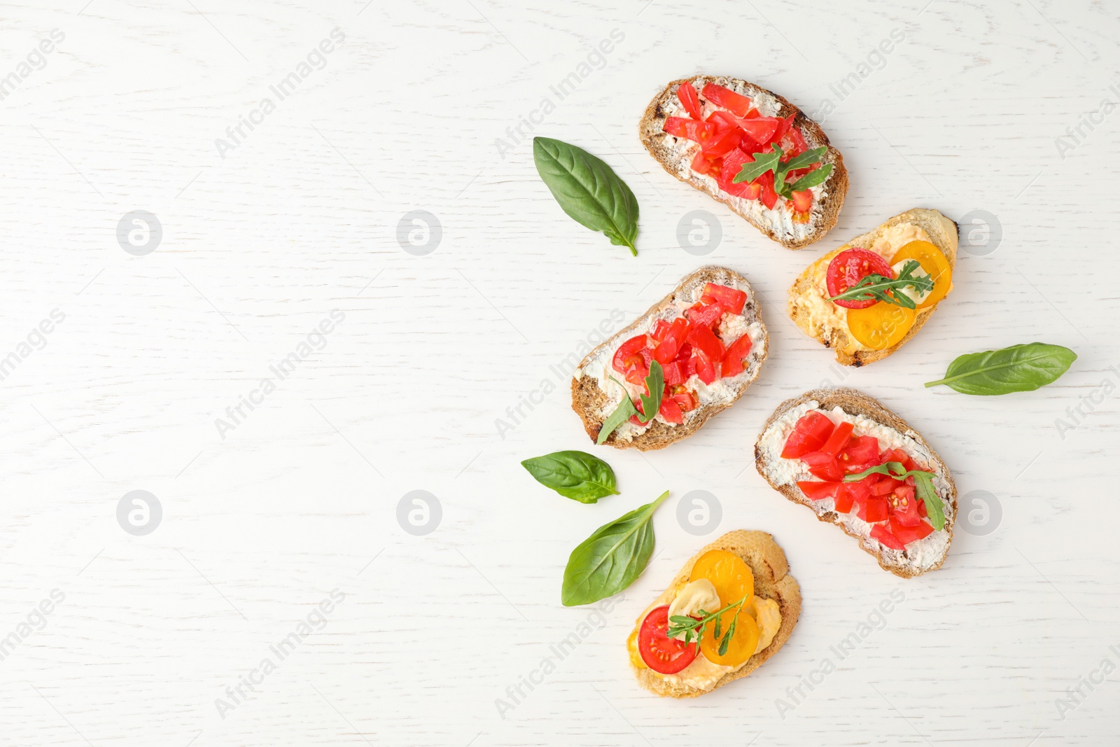 Photo of Delicious tomato bruschettas on white wooden background, flat lay. Space for text