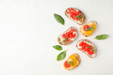 Delicious tomato bruschettas on white wooden background, flat lay. Space for text