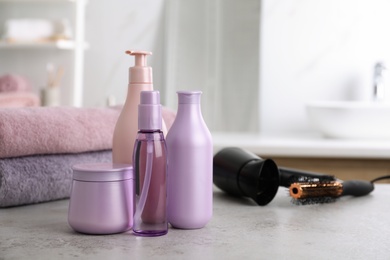 Different hair care products on table in bathroom, space for text