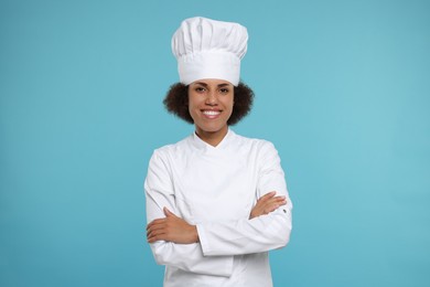 Photo of Portrait of happy female chef in uniform on light blue background