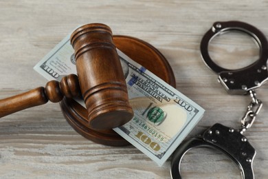 Judge's gavel, money and handcuffs on wooden table