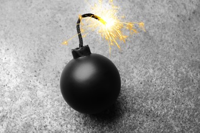 Old fashioned black bomb with lit fuse on grey table