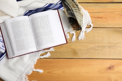 Photo of Tallit, shofar and open Torah on wooden table, flat lay. Rosh Hashanah celebration