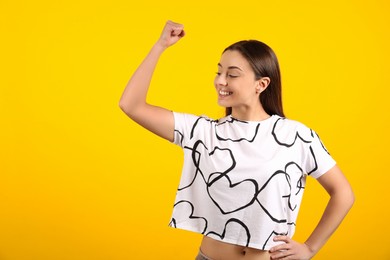 Photo of Strong woman as symbol of girl power on yellow background, space for text. 8 March concept