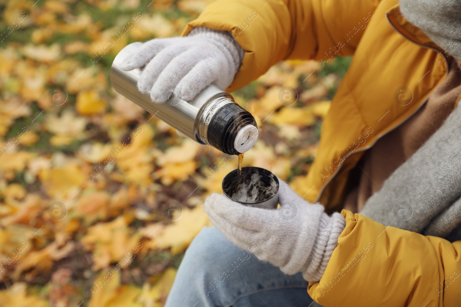 Photo of Woman pouring drink from thermos into cap outdoors, closeup