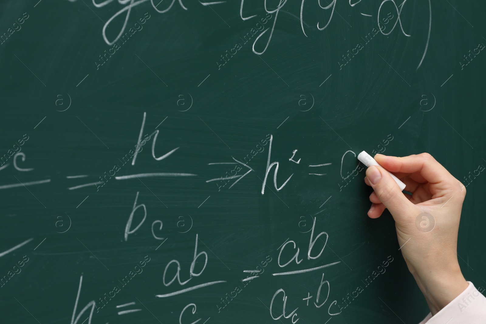 Photo of Teacher writing down math equation on green board, closeup