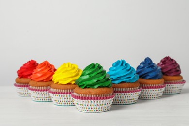Photo of Many delicious colorful cupcakes on white table. Space for text