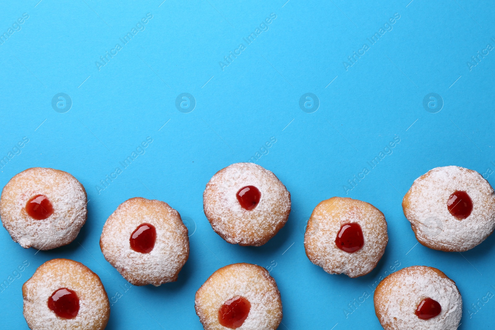 Photo of Hanukkah donuts with jelly and powdered sugar on turquoise background, flat lay. Space for text